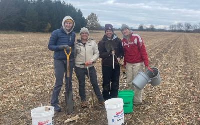 Group of people with soil sampling equipment, standing in a field